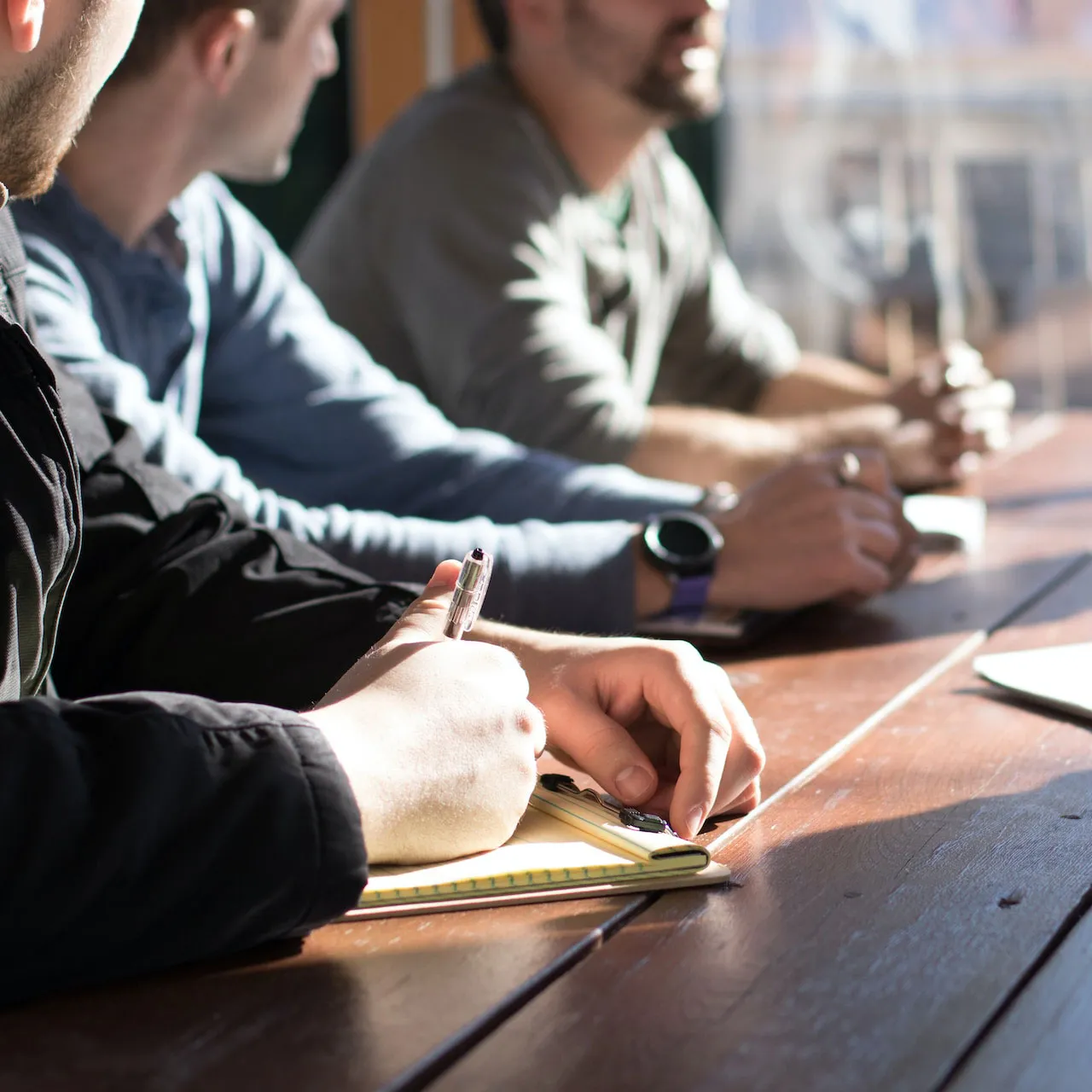 Meeting on software development with people taking notes at a table.