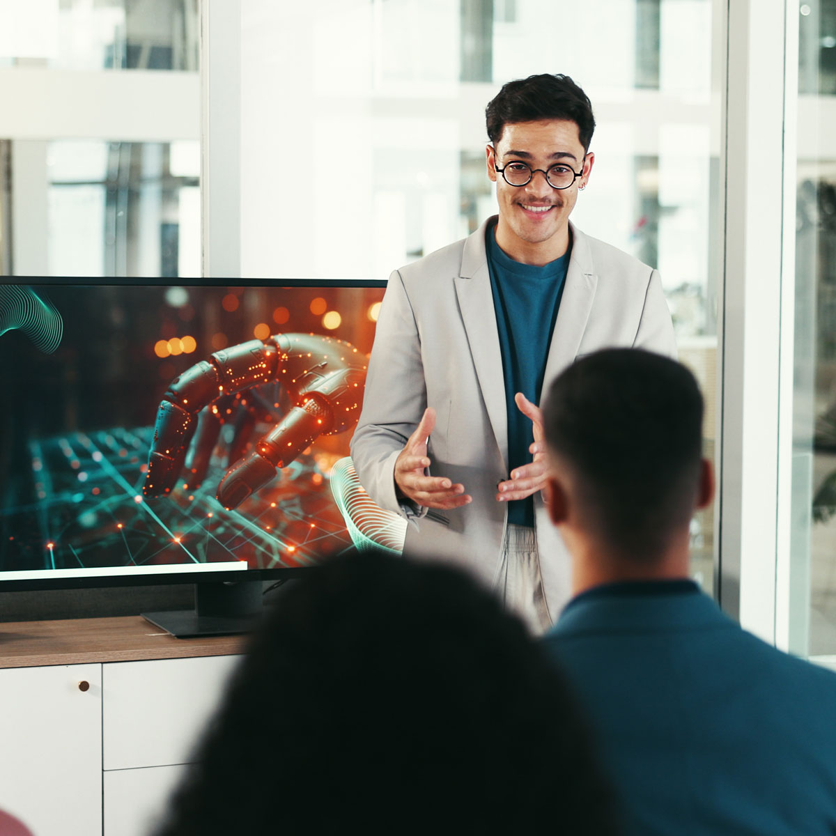 Man presenting tech concepts with robotic hand image on screen to engaged audience.