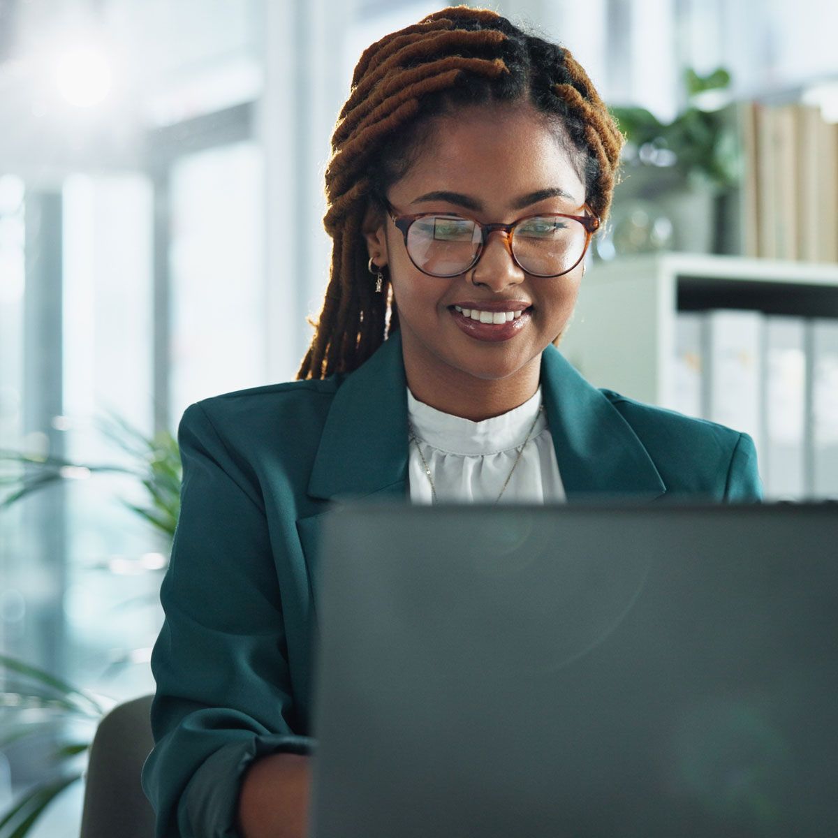 Smiling professional working on laptop, focusing on custom LLM compliance solutions in a modern office setting.