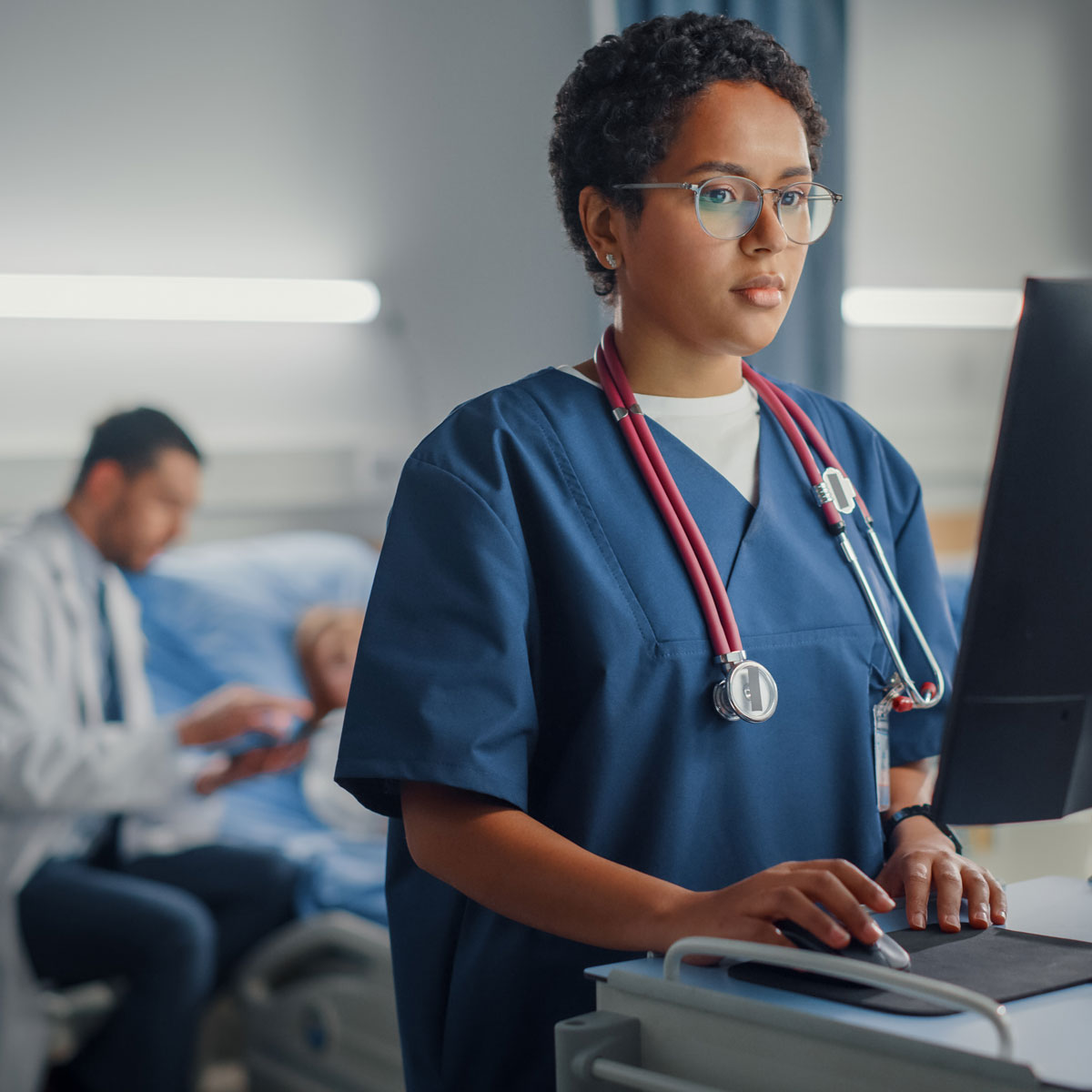Healthcare professional using a AI-driven solutions in a hospital setting with patient in the background.
